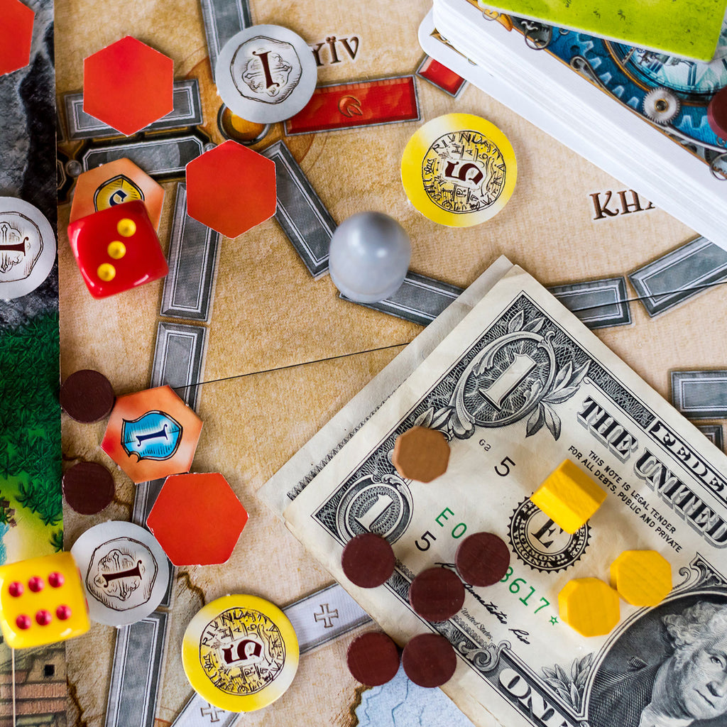 cover image for an article giving tips on how to save money on board games, the picture shows a playing board with tokens and real money